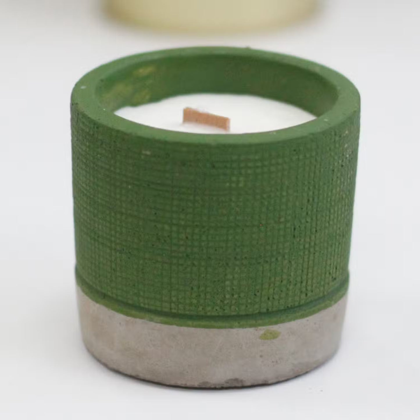 Green textured candle holder with a white candle inside on a white background