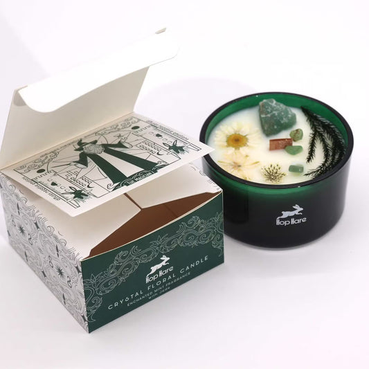 Crystal floral candle in a green container with decorative elements, next to its packaging box on a white background.