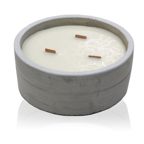 A concrete candle with a wooden wick, containing a white wax, housed in a round concrete pot.
