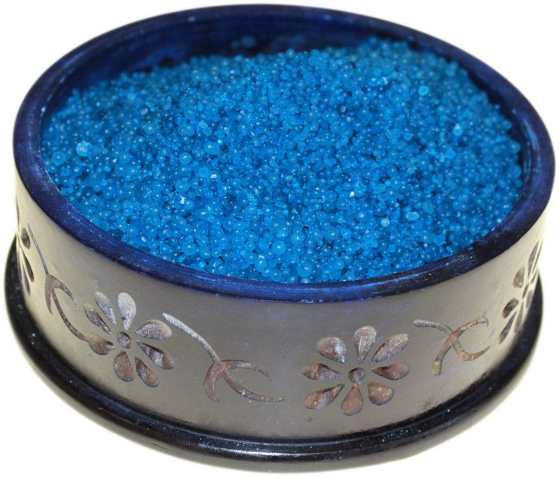 A bowl of blue simmering granules with a floral patterned edge.