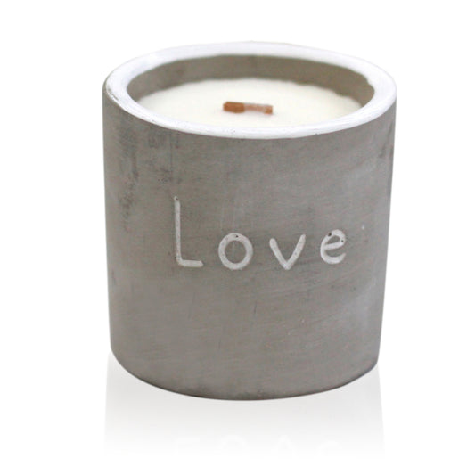 A concrete candle with a wooden wick and the word 'Love' printed on the side, containing a white candle.
